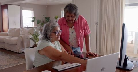 Elderly Friends Engaging with Technology at Home, Strengthening Connections