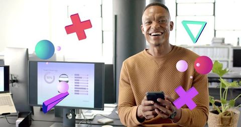 Smiling professional holding phone at modern open-plan desk with colorful digital overlays