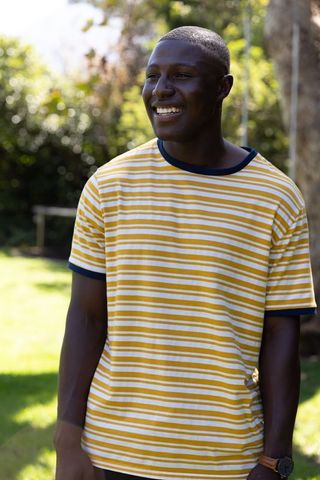 Smiling Man in Sunlit Garden Wearing Striped T-Shirt