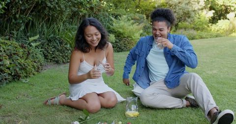 Friends enjoying refreshing drinks in sunny garden picnic