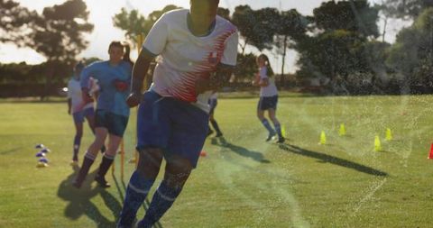 Youth soccer team running agility drills on sunlit field during golden hour