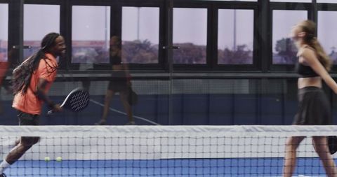 Diverse players enjoy padel tennis match indoors