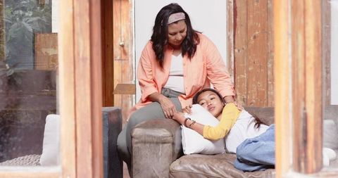 Mother consoling daughter on stylish living room sofa