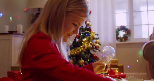 Excited Girl Holding Christmas Ornament by Tree - Download Free Stock Images Pikwizard.com