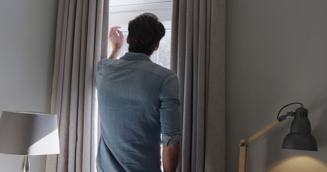 Man in Denim Shirt Opening Window Curtains in Cozy Room, Morning Light Coming In - Download Free Stock Images Pikwizard.com