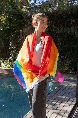 Woman Embracing Joyful Spirit Wrapped in Pride Flag by Poolside