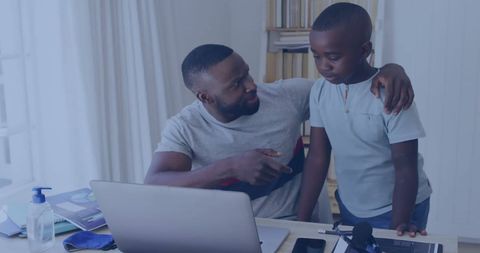 Father Teaching Son at Home with Laptop and Books