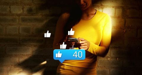 Woman holding smartphone receiving 40 likes notification in moody loft portrait spotlight