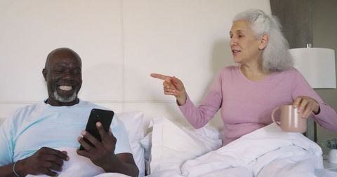 Senior Couple Relaxing in Bed Engaging in Daily Routine