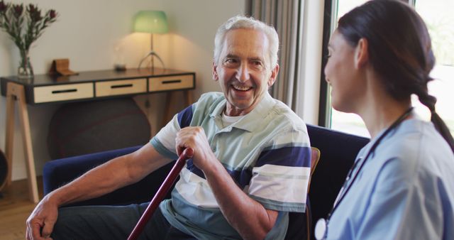 Senior man sitting in living room chatting with nurse. Ideal for topics on elderly care, home health care support, and caregiving services. Can be used for healthcare brochures, nursing services websites, and promotional materials for elderly assistance programs.