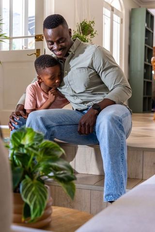 African american father embracing son on home steps showing warmth, bond and affection
