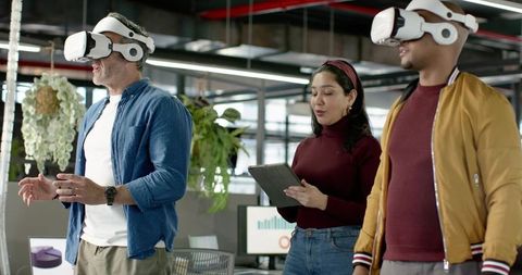 Multicultural team exploring virtual reality collaboration in modern office with greenery
