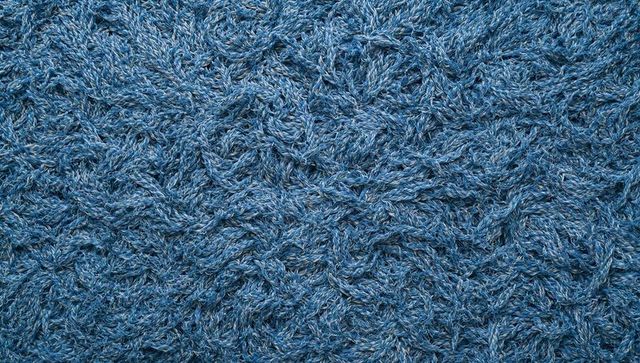 Blue shag rug texture featuring twisted yarn strands, variegated flecks and braided detail