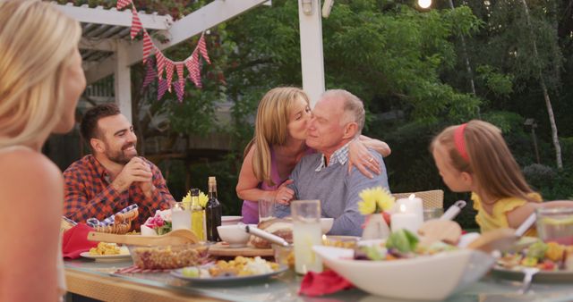 Happy caucasian grandparents embracing and kissing at family dinner table in garden - Download Free Stock Photos Pikwizard.com