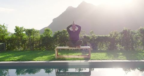 Asian Woman Meditating by Pool in Natural Mountain Setting