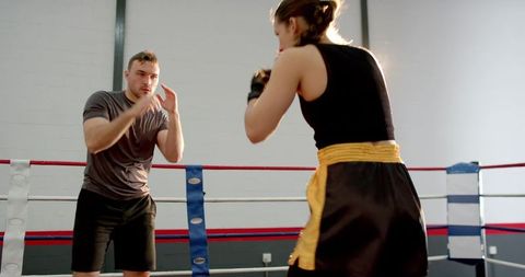 Female Boxer Sparring with Male Coach in Ring Training Focused Boxing Technique