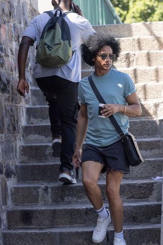 African american men walking on sunlit stone steps holding coffee cup and talking on phone