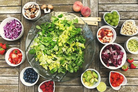 Fresh green salad bowl sitting among colorful fruit and vegetable bowls for healthy meals