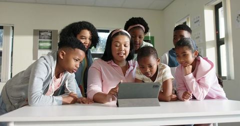 African American teacher engaging diverse students using tablet for group learning