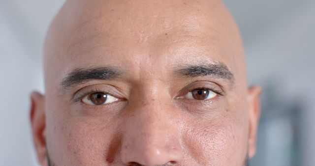 This image features a close-up of a bald man with a serious expression and an intense gaze. It highlights the facial details, making it suitable for use in articles, advertisements, and campaigns related to emotions, personality traits, mental health, or human experiences. It can also be used in projects emphasizing male imagery or mature masculinity.