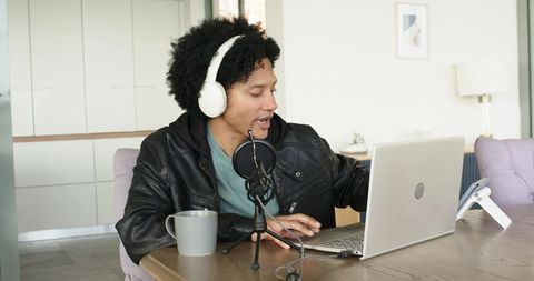 Mid-adult african american podcaster recording at home with laptop, microphone, headphones