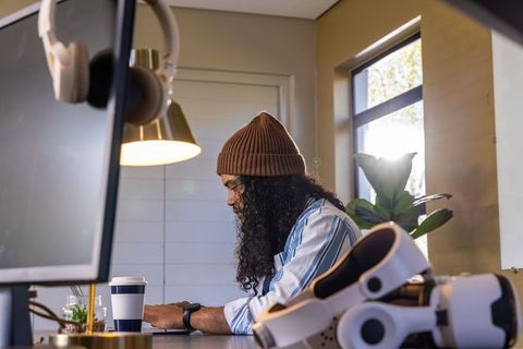 Remote worker typing on laptop in cozy home office with vr headset and coffee