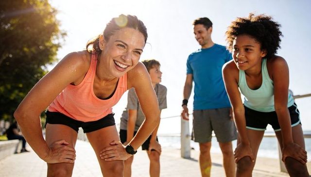Active family taking waterfront fitness break, smiling woman in coral tank top