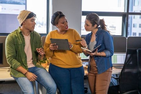 Diverse Coworkers Collaborating Over Tablet and Notebook in Modern Open-Plan Office