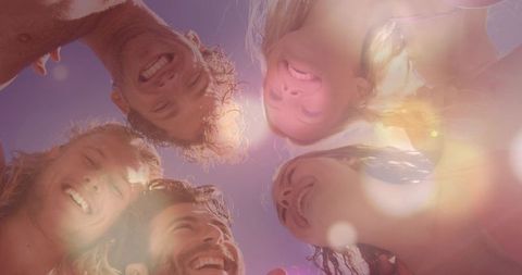 Carefree sunlit beach friendship circle laughing faces backlit sunny summer fun lens flare