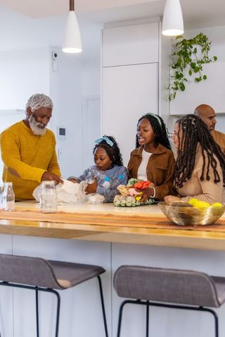 Multigenerational african american family unpacking groceries and eggs at kitchen island