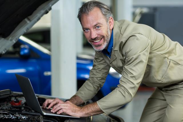 Portrait of mechanic using laptop in repair garage