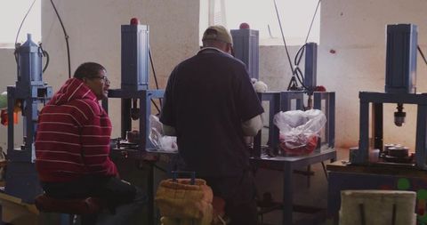 Technicians Operating Hydraulic Press Machines in Manufacturing Workshop