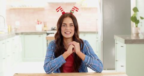 Festive Woman Presenting Christmas Recipe in a Rustic Kitchen