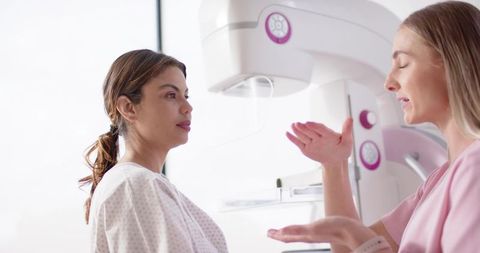 Woman undergoing mammogram while technologist explaining breast imaging procedure