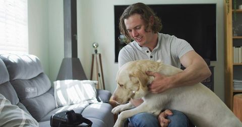 Relaxed young man enjoying time with dog at home with vr headset nearby