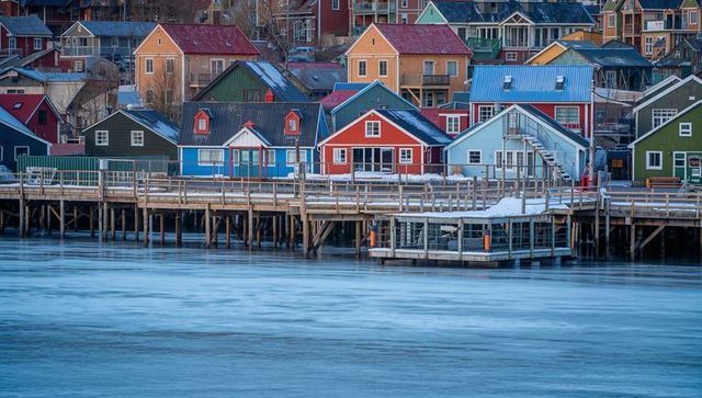 Colorful waterfront houses sitting on wooden stilts at snowy coastal quay with boardwalk