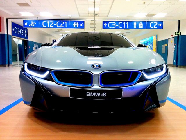 Futuristic BMW i8 showcased in a modern airport terminal. Ideal for use in articles discussing electric vehicles, cutting-edge automotive technology, luxury car reviews, and sustainable transportation solutions.