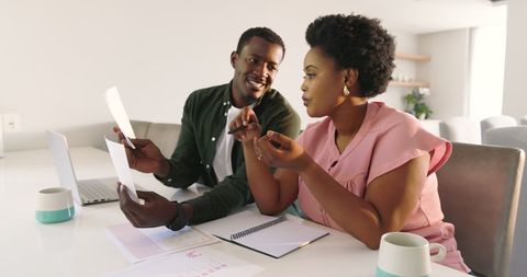 Friends collaborating over documents at home with coffee