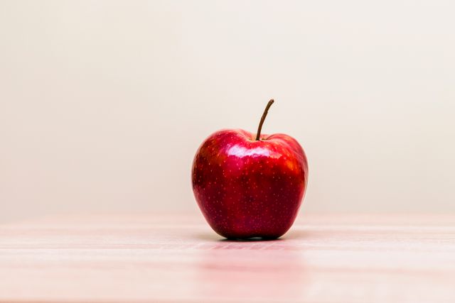 Shiny Red Apple on Light Wooden Table with Plain Background - Download Free Stock Photos Pikwizard.com