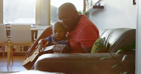 Father Teaching Son Guitar in Sunlit Living Room