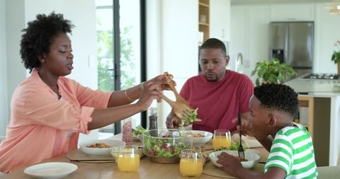 African american family enjoying mealtime at sunlit modern kitchen table