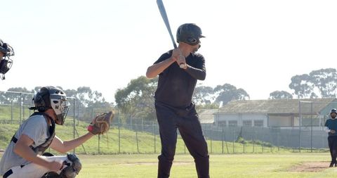 Batter swinging at home plate with catcher receiving and umpire watching on baseball field