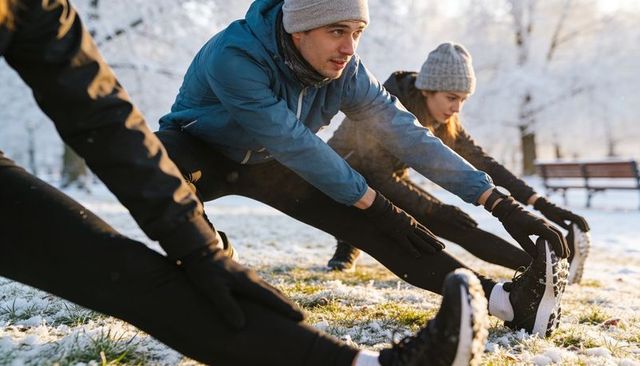 Group stretching on snowy park grass morning run warm-up for winter outdoor fitness