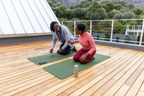 African american couple practicing yoga on rooftop deck, outdoor fitness and wellness