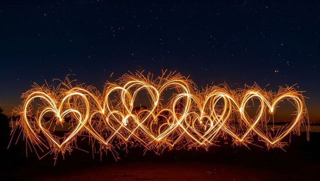 Drawing Sparkler Heart Light Trails Along Coastline at Twilight Under Starry Sky