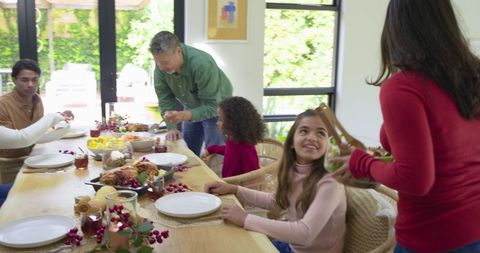 Multigenerational diverse family sharing holiday meal at sunlit dining table