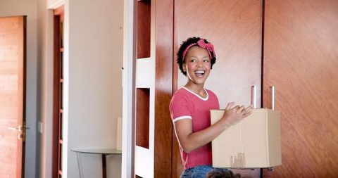 Joyful Woman Holding a Box in New Home