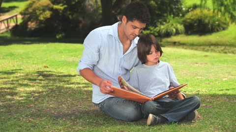 Father and Son Enjoying Album in Park