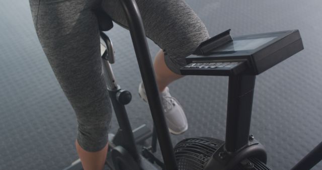 This image shows a woman exercising on a stationary bike in a gym. Ideal for use in fitness-related articles, workout guides, exercise promotions, and healthy lifestyle blogs. Can be used to promote gym memberships, fitness equipment, and cardio exercise routines.