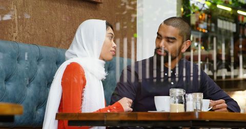 Middle eastern couple conversing at cafe over coffee